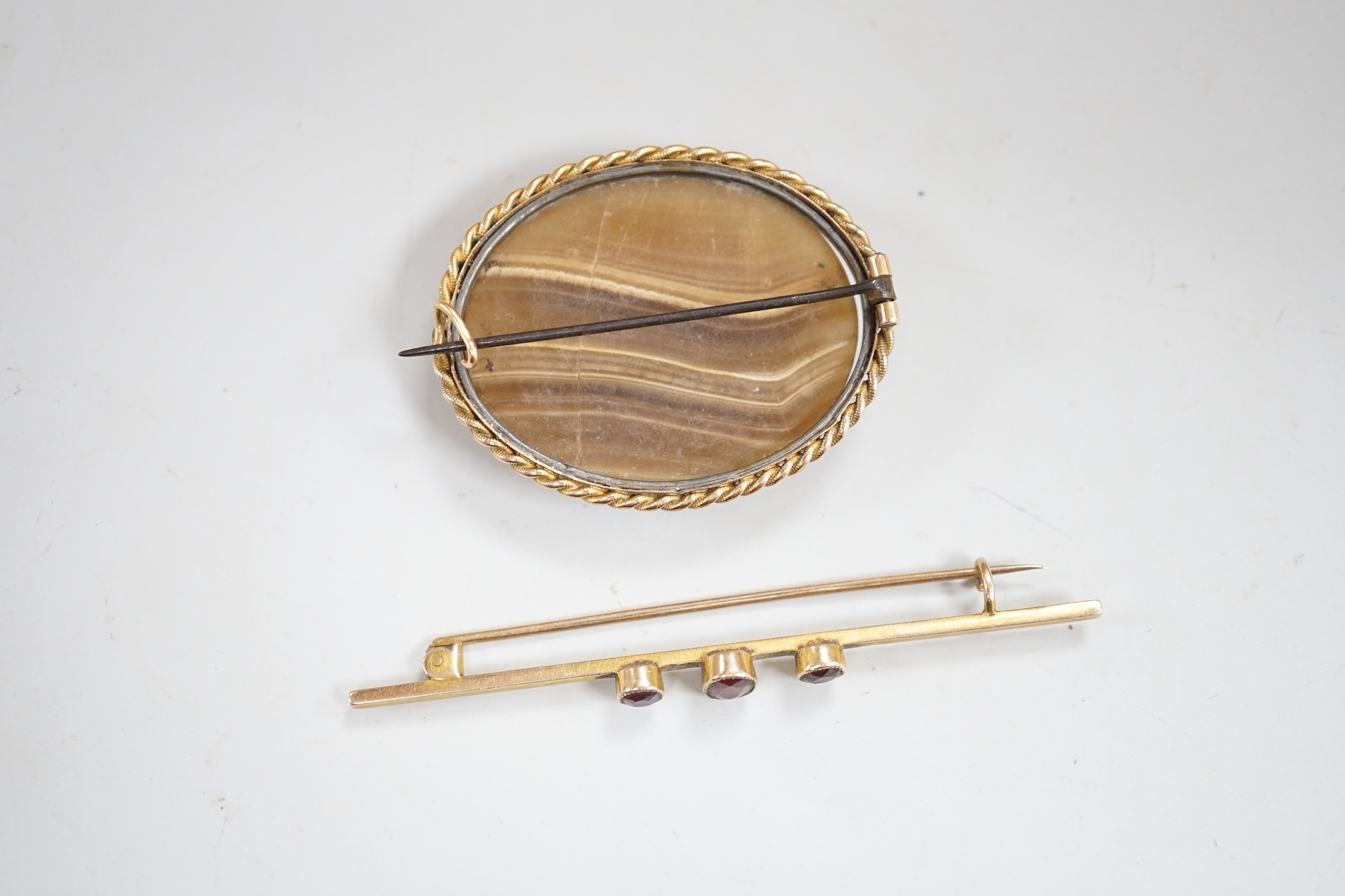 An early 20th century yellow metal and three stone garnet? set bar brooch, 72mm and one other brooch.